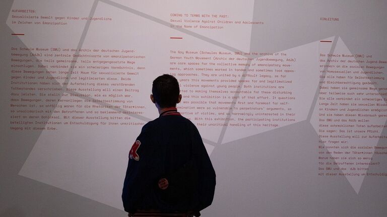 Modernes Foto: Ein Mensch liest einen Text, der auf einer Wand aufgebracht ist.