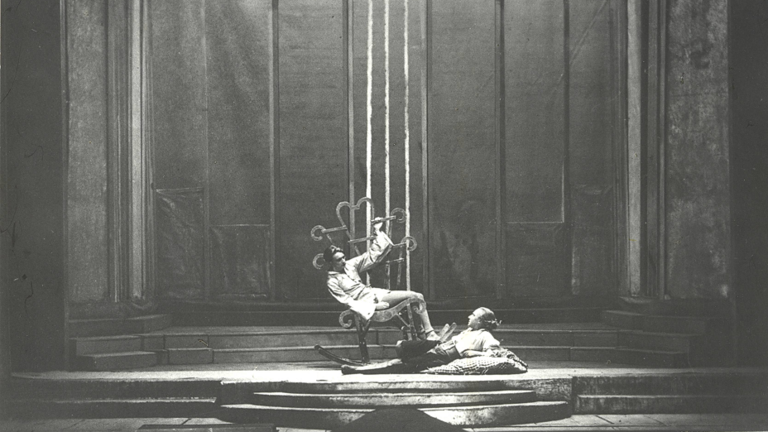 Historisches Foto: Zwei Personen auf einer leeren Bühne, im Hintergrund Kulissen