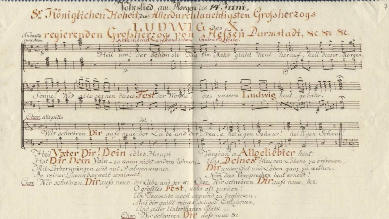 Musiknoten mit Text (Chor mit Klavierbegleitung) auf einem Schmuckblatt