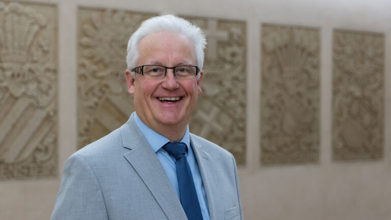 Lachender Mann mit weißen Haaren, Anzug und Brille
