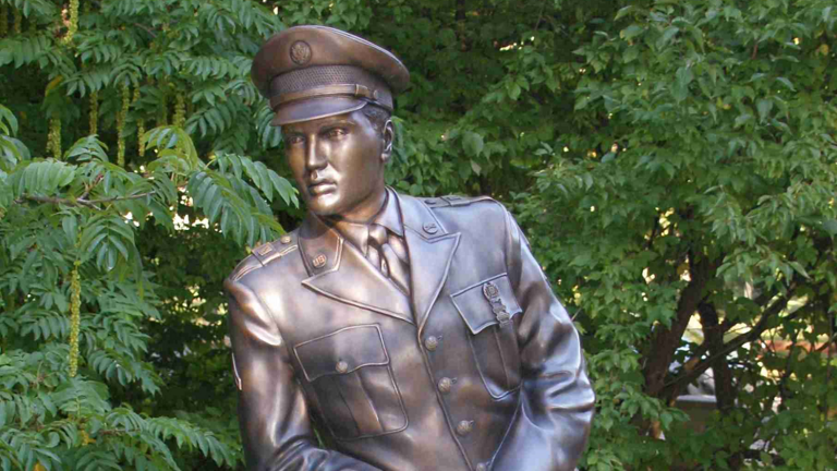 Modernes Foto: bronzene Statue eines Mannes in Uniform mit Mütze, an einem Brückengeländer angelehnt