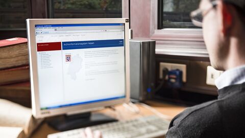 Recherche im Archivinformationssystem Arcinsys: Ein Mann blickt auf einen PC-Monitor mit der Startseite von Arcinsys.