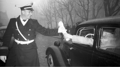 Ein Autofahrer reicht einem Verkehrspolizisten ein Weihnachtsgeschenk, 1952 (HHStAW, 3008/2, 9760) Ein Autofahrer reicht einem Verkehrspolizisten ein Weihnachtsgeschenk, 1952 (HHStAW, 3008/2, 9760)