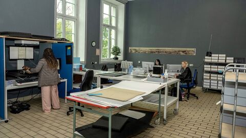 Blick in die Fotowerkstatt im Staatsarchiv Darmstadt Modernes Foto: Fotowerkstatt mit Scanner, Arbeitstischen mit Materialien, Archivwagen und Mitarbeiterinnen an ihren Arbeitsplätzen