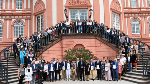 Gütesiegel „Familienfreundlicher Arbeitgeber Land Hessen“ und „Familienfreundliche Hochschule Land Hessen“ bereits zum zehnten Mal durch das Innenministerium verliehen Foto: Alle Beteiligten bei der Verleihung der Gütesiegel stehen auf den Stufen verteilt auf der Treppe des Schloss Biebrich