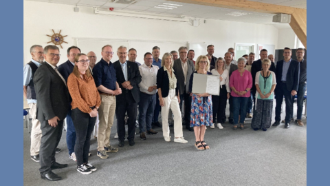 Gemeinsame Vorsorge: der Notfallverbund Modernes Foto: Gruppe von Männern und Frauen, im Vordergrund präsentiert eine Frau ein Schriftstück