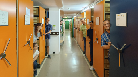 Modernes Foto: Auszubildende schauen zwischen den Regalen im Magazin hervor