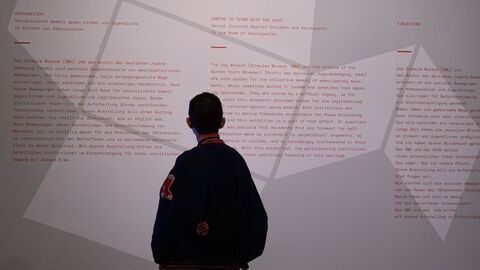 Ausstellung zur Aufarbeitung Sexualisierter Gewalt gegen Kinder und Jugendliche Modernes Foto: Ein Mensch liest einen Text, der auf einer Wand aufgebracht ist.