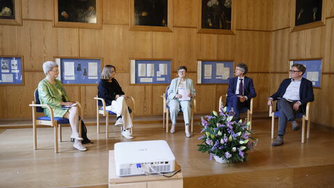 Podiumsdiskussion Drei Frauen und zwei Männer sitzen auf einem Podium und diskutieren