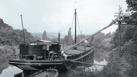 Beladung eines Frachtschiffs an der Lahn, um 1950 (Foto: Lahnkanal-Verein, HWA Bestand 30 Nr. 54103) Historisches Foto: Festgemachtes Frachschiff, das durch eine Förderanlage beladen wird