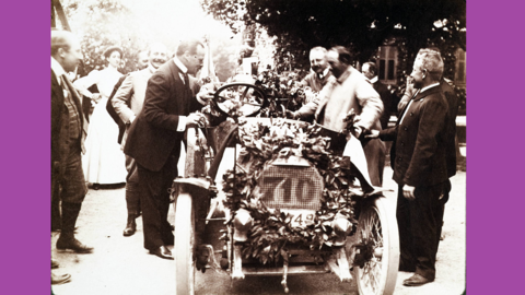 Historisches Foto: Männer umringen einen blumengeschmückten Rennwagen