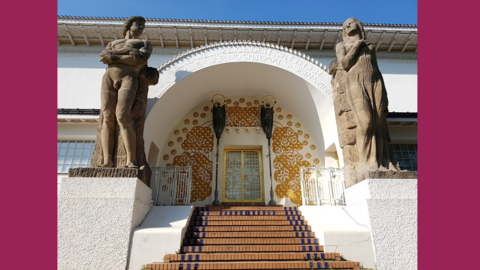 Treppe und Portal des "Ernst-Ludwig-Hauses" auf der Mathildenhöhe, 2025 Foto: Treppenaufgang, flankiert von zwei großen Statuen, und Portal eines Hauses in auffällig runder Form.