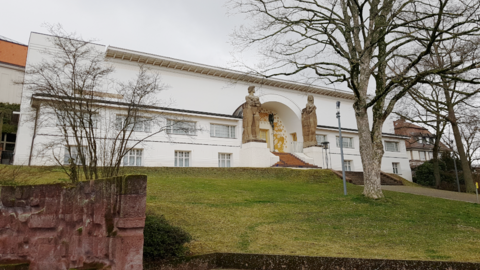 Kantige klare Formen: Das "Ernst-Ludwig-Haus" auf der Mathildenhöhe in Darmstadt, 2025 Foto: Weißes Haus in kantigen Formen auf einem kleinen grasbewachsenen Hügel mit einem markanten Baum