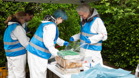 Erstversorgung der Unterlagen nach der Bergung. Personen in blau-weißer Schutzkleidung