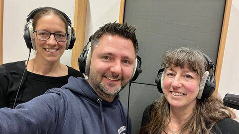 Das Moderationsduo mit seinem ersten Gast Dr. Eva Bender. zwei Frauen und ein Mann stehen nebeneinander und tragen Kopfhörer