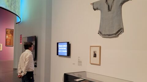 Zu sehen sind auch Exponate aus dem Archiv der deutschen Jugendbewegung, u. a. ein Reformkittel Ein Mann steht vor einer Vitrine, an der Wand hängt ein Kittel