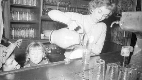 Mit Freude wird der Apfelwein in den Gaststätten ausgeschenkt! in schwarz-weiß: Eine Frau gießt Wein aus einer Karaffe in Gläser