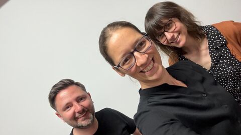 Ein Mann und zwei Frauen lachen in die Kamera