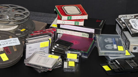 Audiovisuelle Medien werden dem Archiv häufig angeboten auf einem Tisch liegen mehrere Tonbänder, Videokassetten und Disketten