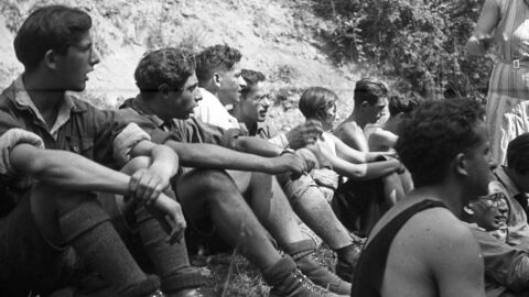 schwarz-weiß Foto von jungen Menschen die im freien nebeneinander sitzen