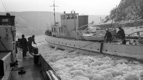 Historisches Foto: Zwei parallel fahrende Schiffe, dazwischen dicke Eisschollen. Die Besatzung versucht, mit einer Hakenstange ein Tau überzuholen.