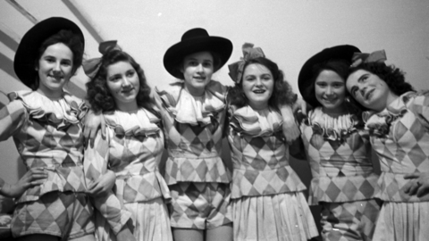 Historisches Foto: sechs junge Frauen in kurzen Tanzkostümen mit Rautenmuster, drei mit Hut, drei mit Haarschleifen