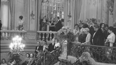 schwarz-weiß Foto von vielen elegant und festlich gekleideten Menschen in einem imposanten Foyer